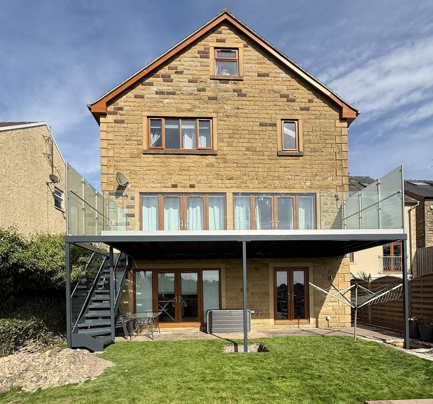 Walk-out balcony and external steel staircase across the rear of a stone house in Dronfield