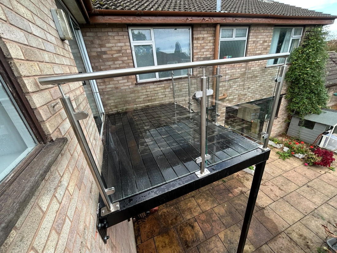 Replacement steel walk out balcony with anthracite grey composite decking and a glass balustrade, fitted to a Nuneaton house