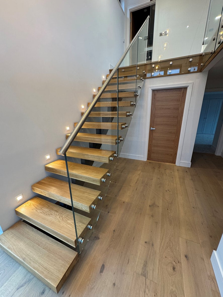 Steel spine staircase with deep oak treads and a frameless glass balustrade, supplied to Jersey
