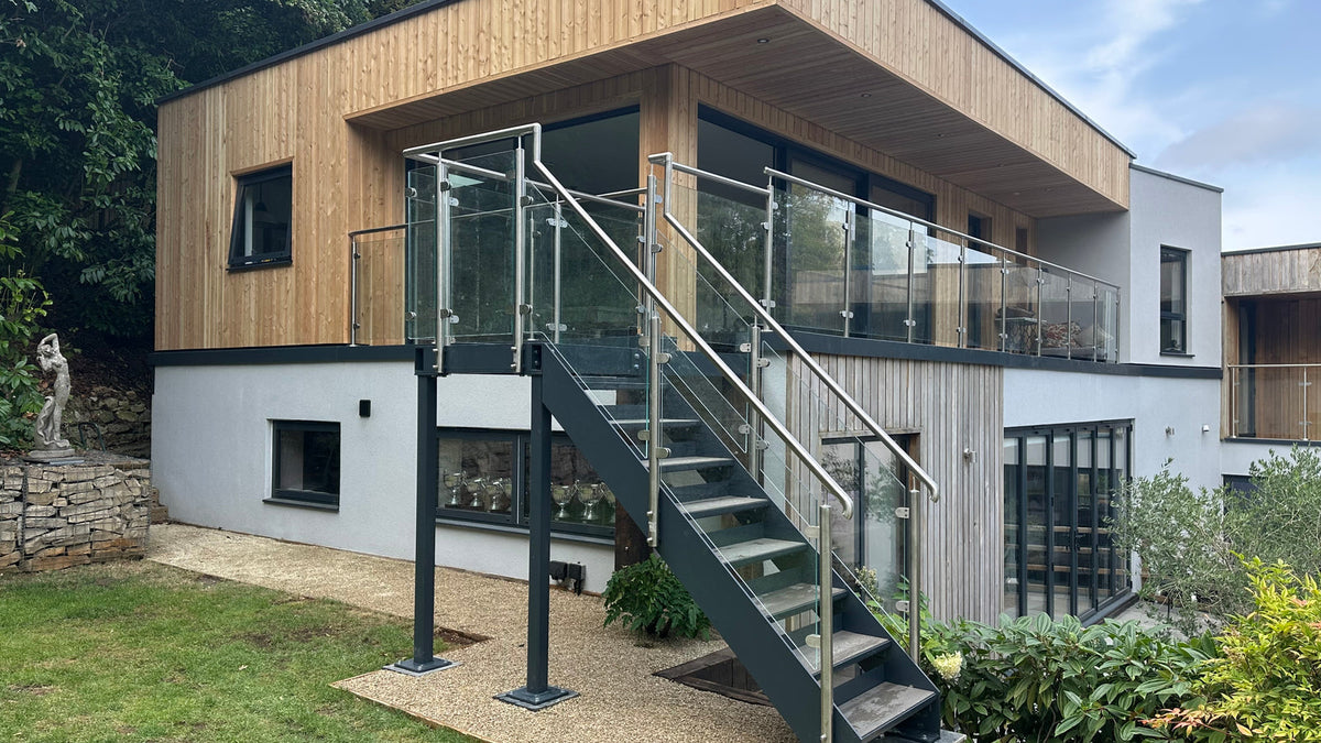 Powder coated external steel staircase with glass balustrade on a modern timber clad house