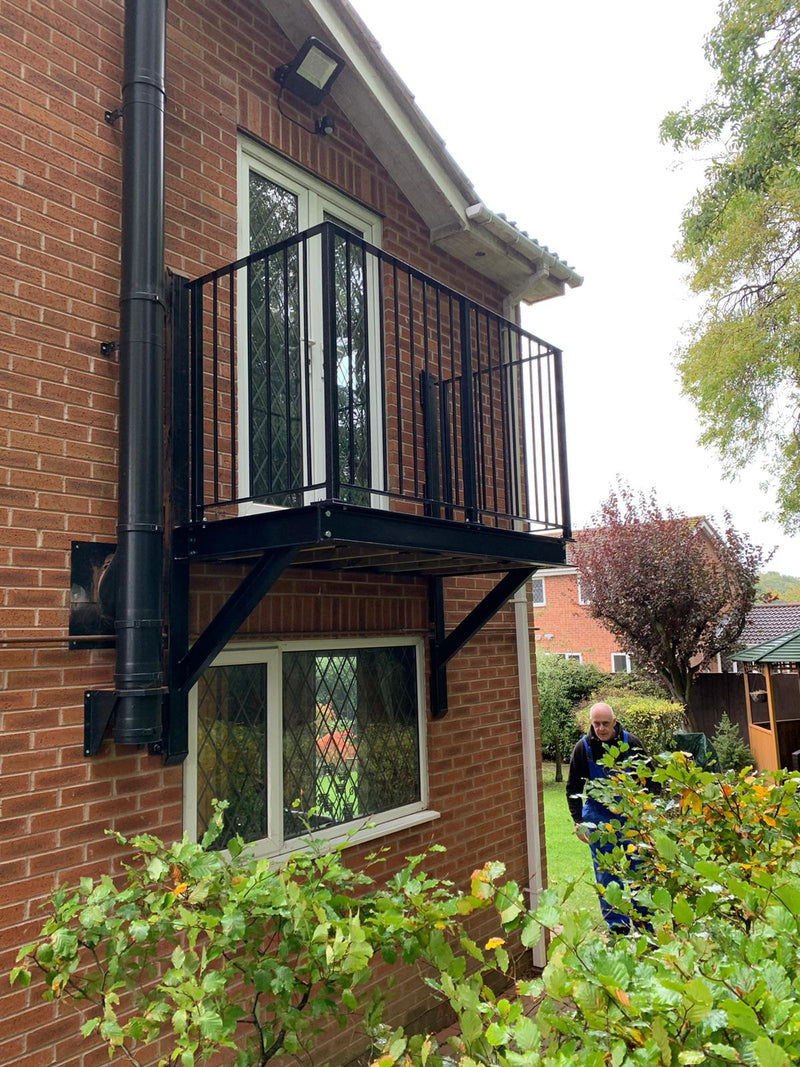 Step-out balcony with metal balustrade projecting from a brick wall on steel brackets