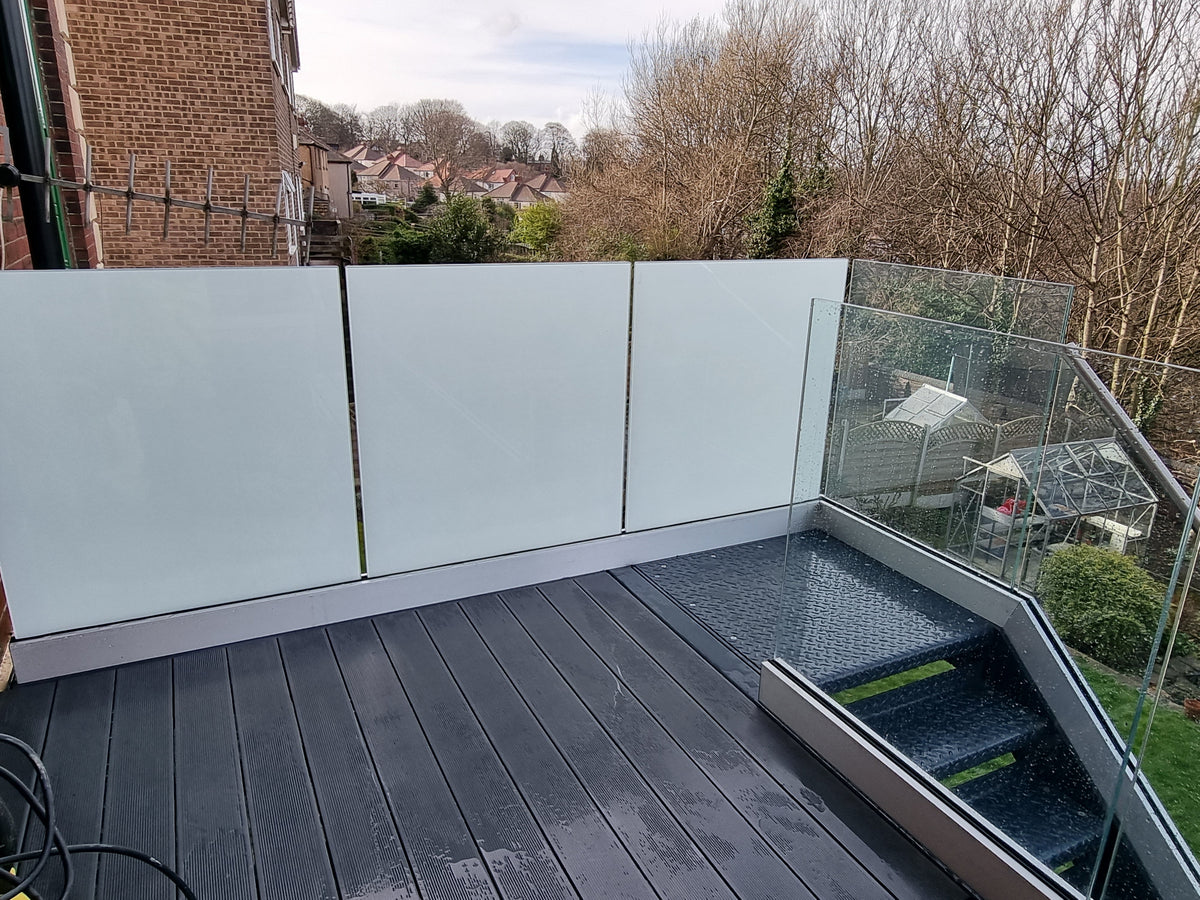 Frosted glass privacy panels screening one side of a roof terrace, with clear frameless glass to the open side