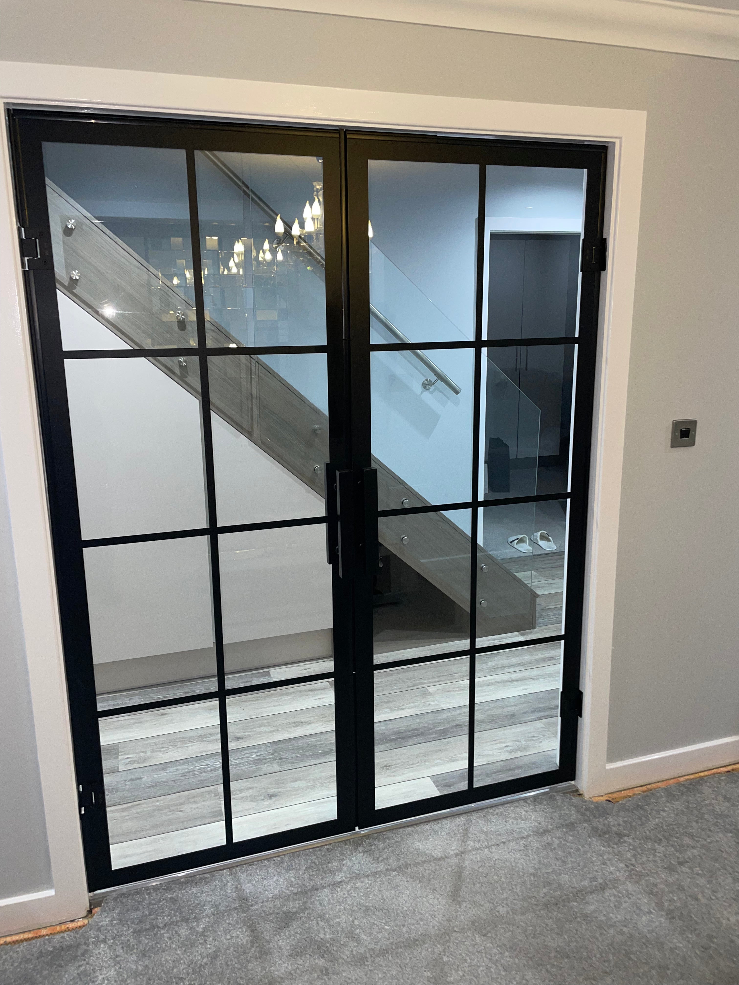 Frameless glass partition doors closed across a room opening