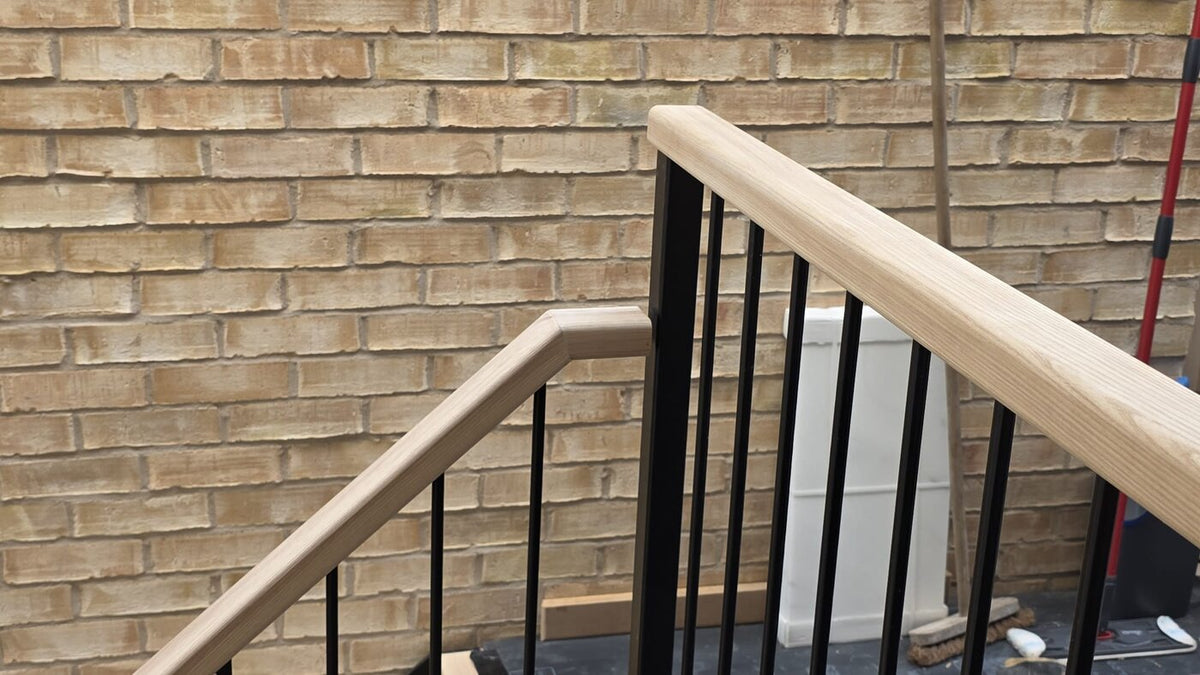 Solid ash handrail mitred over a black powder coated metal balustrade with 12mm bar infills