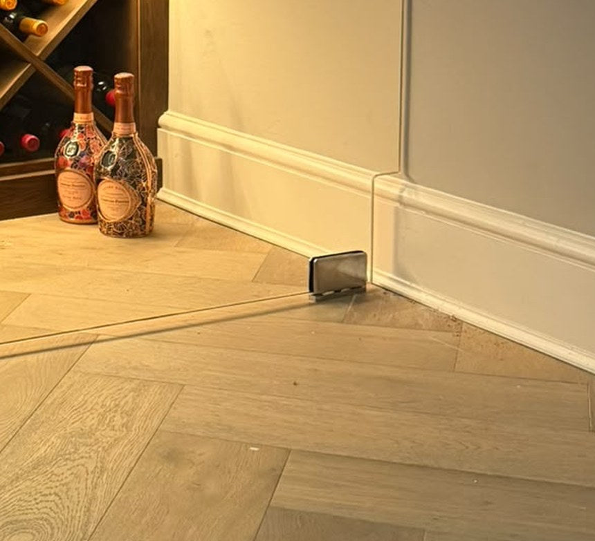 Glass door notched around the skirting on a stainless patch hinge