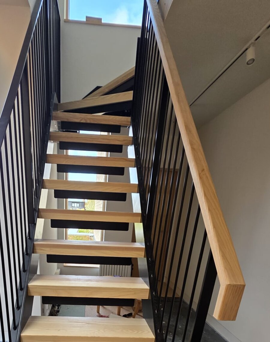 Kite winder turning at the head of a steel feature staircase with ash treads and a metal balustrade