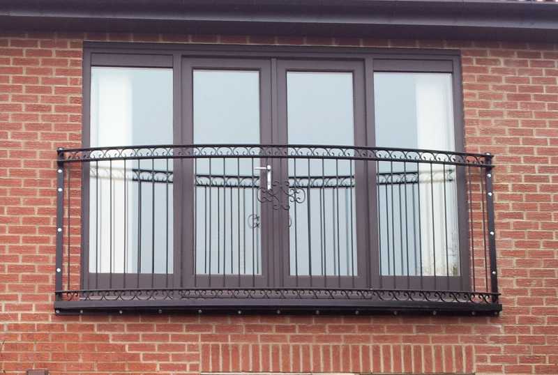 Curved ornate steel Juliet balcony with scroll patterns and a steel mesh floor