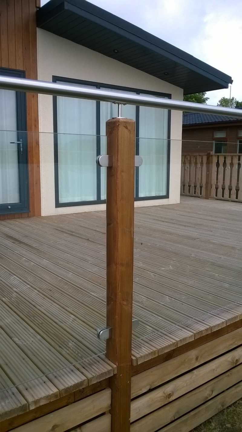 Home decking balustrade with glass infill and a tubular top rail on upstand brackets