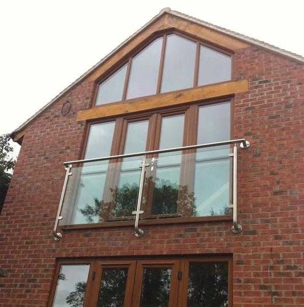 Stainless steel and glass Juliet balcony with intermediate posts and a handrail over