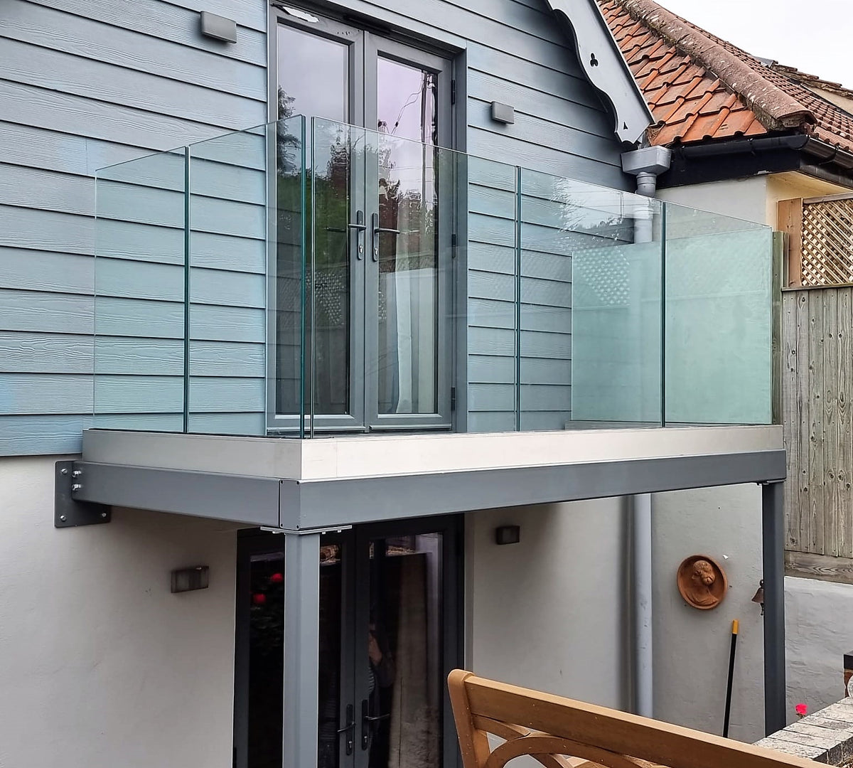 Frameless glass walk-out balcony over a garden, with no posts interrupting the view