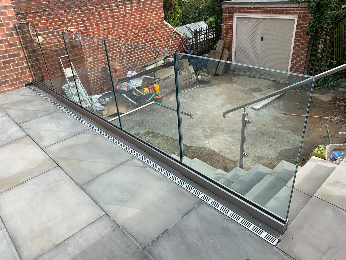Laminated glass panels in a base channel guarding a patio and stair opening