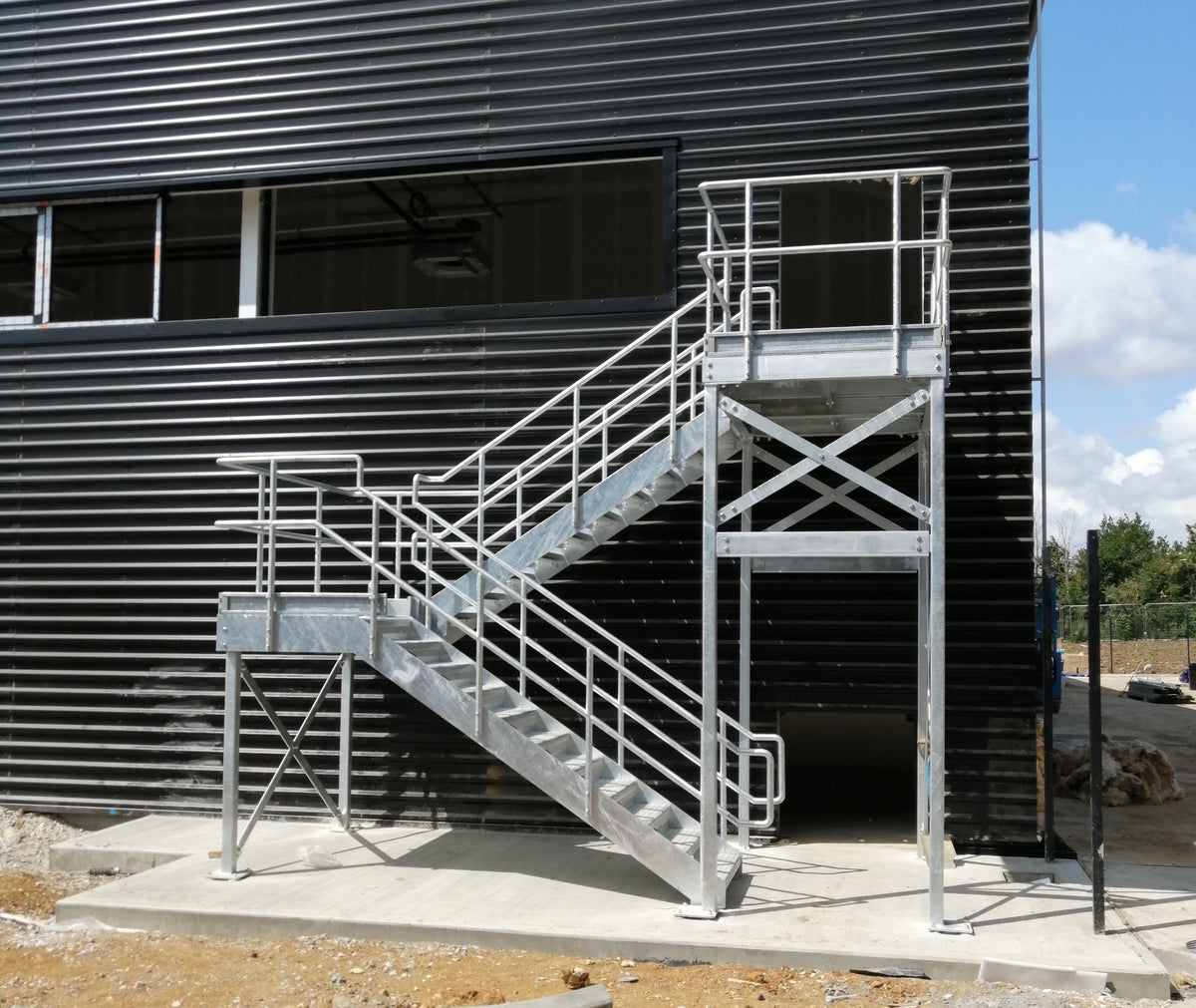 Multi flight galvanised steel fire escape staircase and platform on a clad industrial building