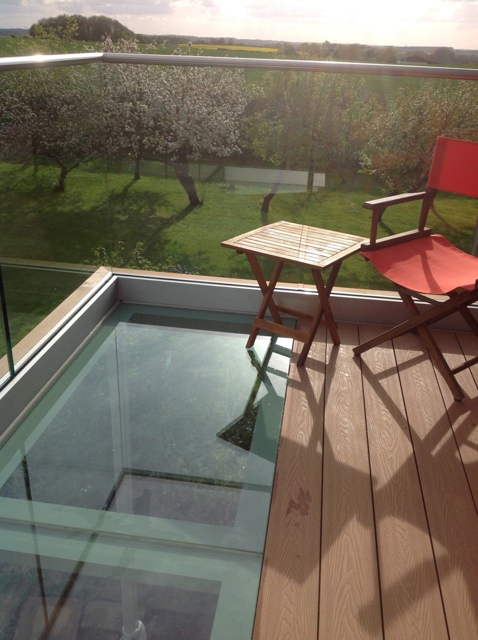 Looking down through a walk-on glass balcony floor onto the terrace and seating below