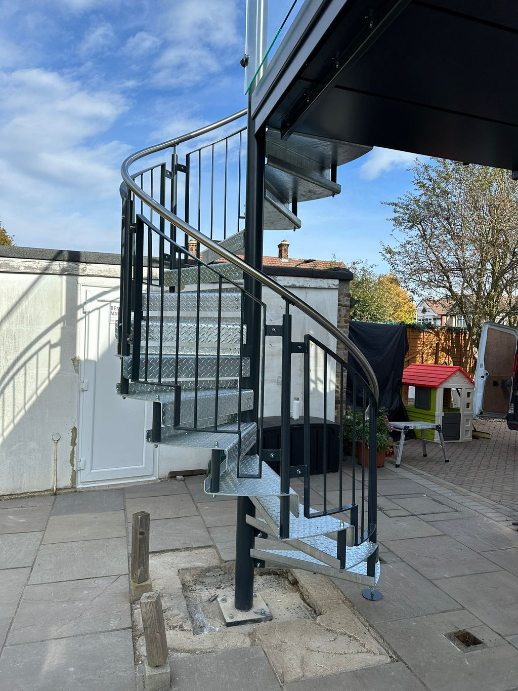 Steel spiral staircase under a balcony with galvanised treads