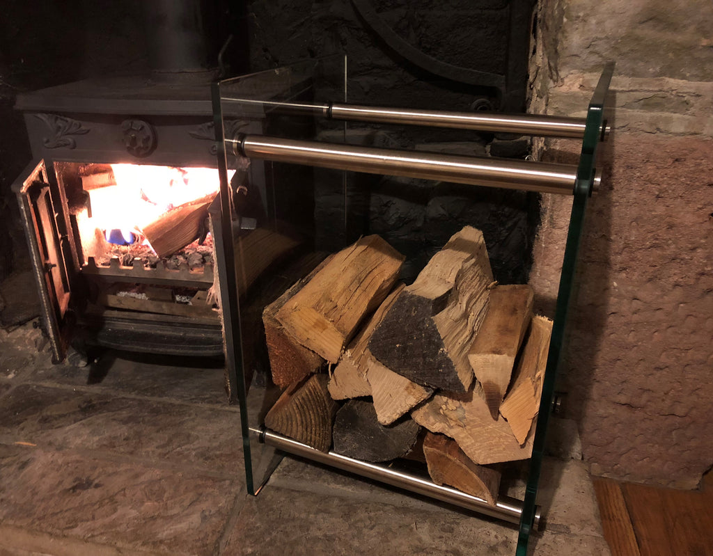 Toughened glass log rack holding split logs in a living room