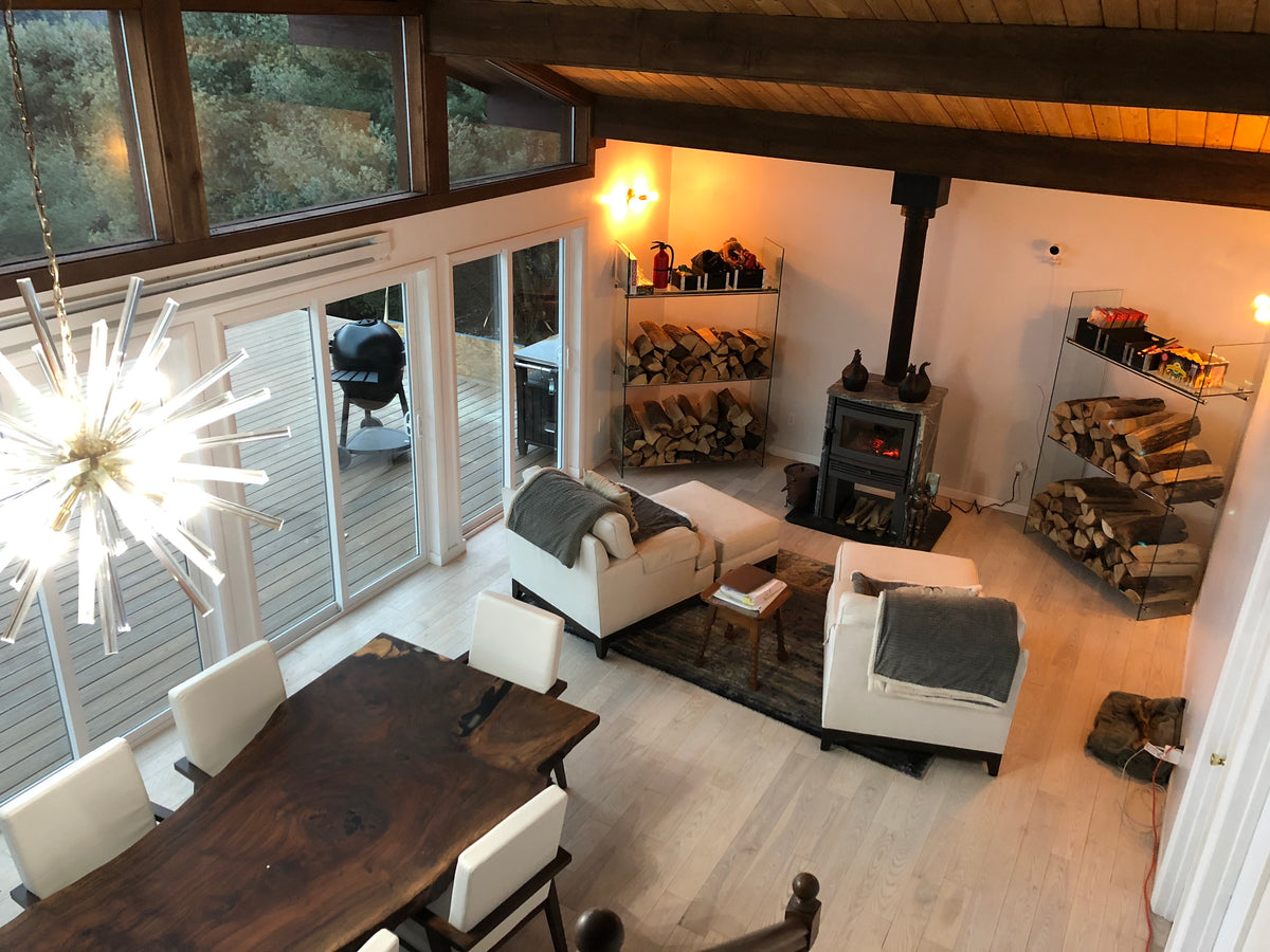 Glass log rack with stainless steel cross rails beside a wood burning stove