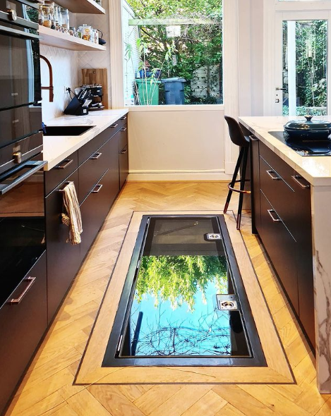 Large hinged glass floor hatch in a kitchen, lifted open