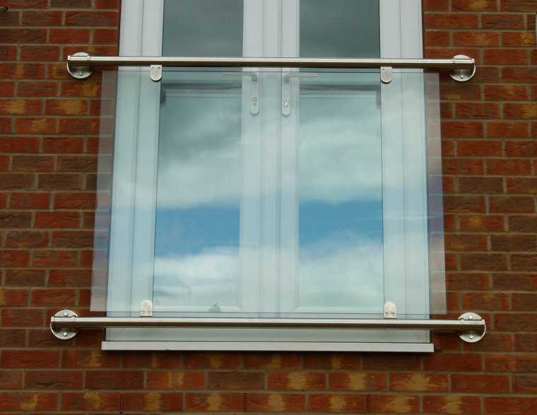 Glass Juliet balcony in stainless steel clamps between tubular top and bottom rails