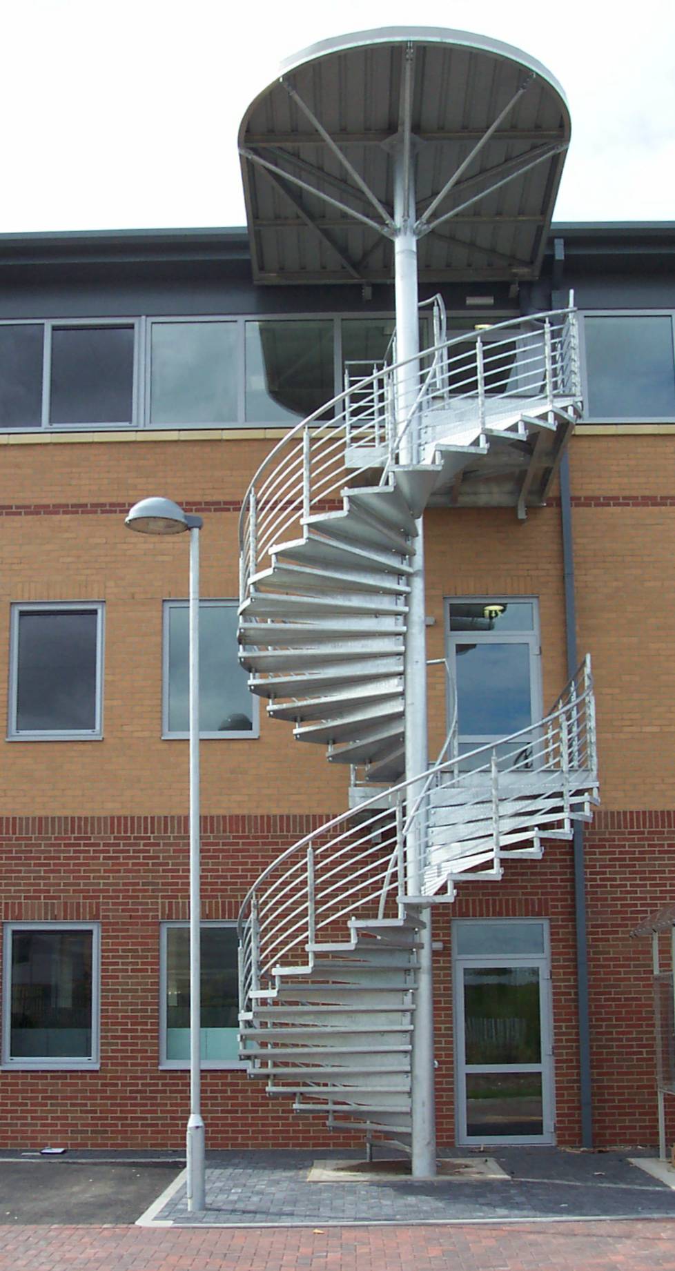 Galvanised steel spiral staircase with canopy roof on a commercial building