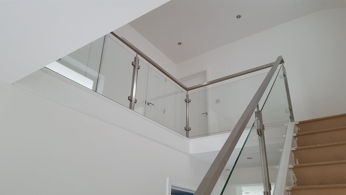 Low iron glass balustrade to a landing and stair flight with a stainless steel handrail