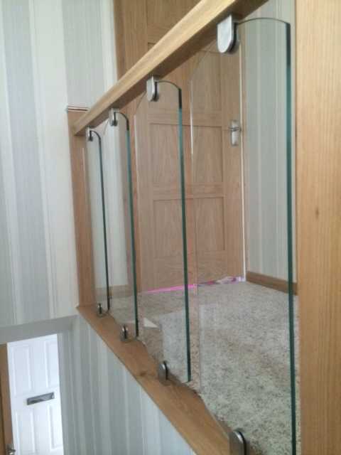 Shaped toughened glass panel fitted to a staircase in stainless clamps