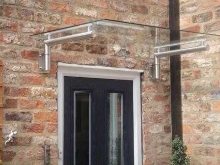 Glass canopy fixed back to a wall using stainless adaptor brackets