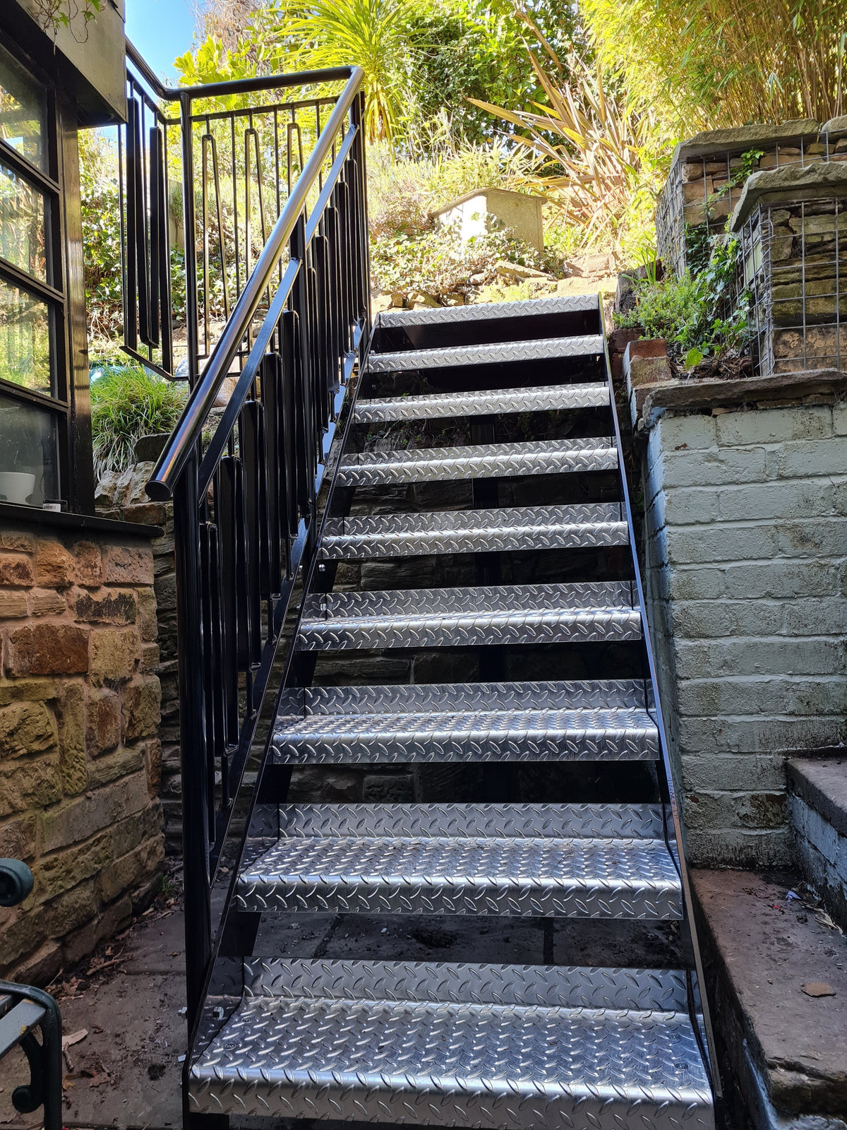 Black powder coated external steel staircase with metal railings and galvanised chequer plate treads