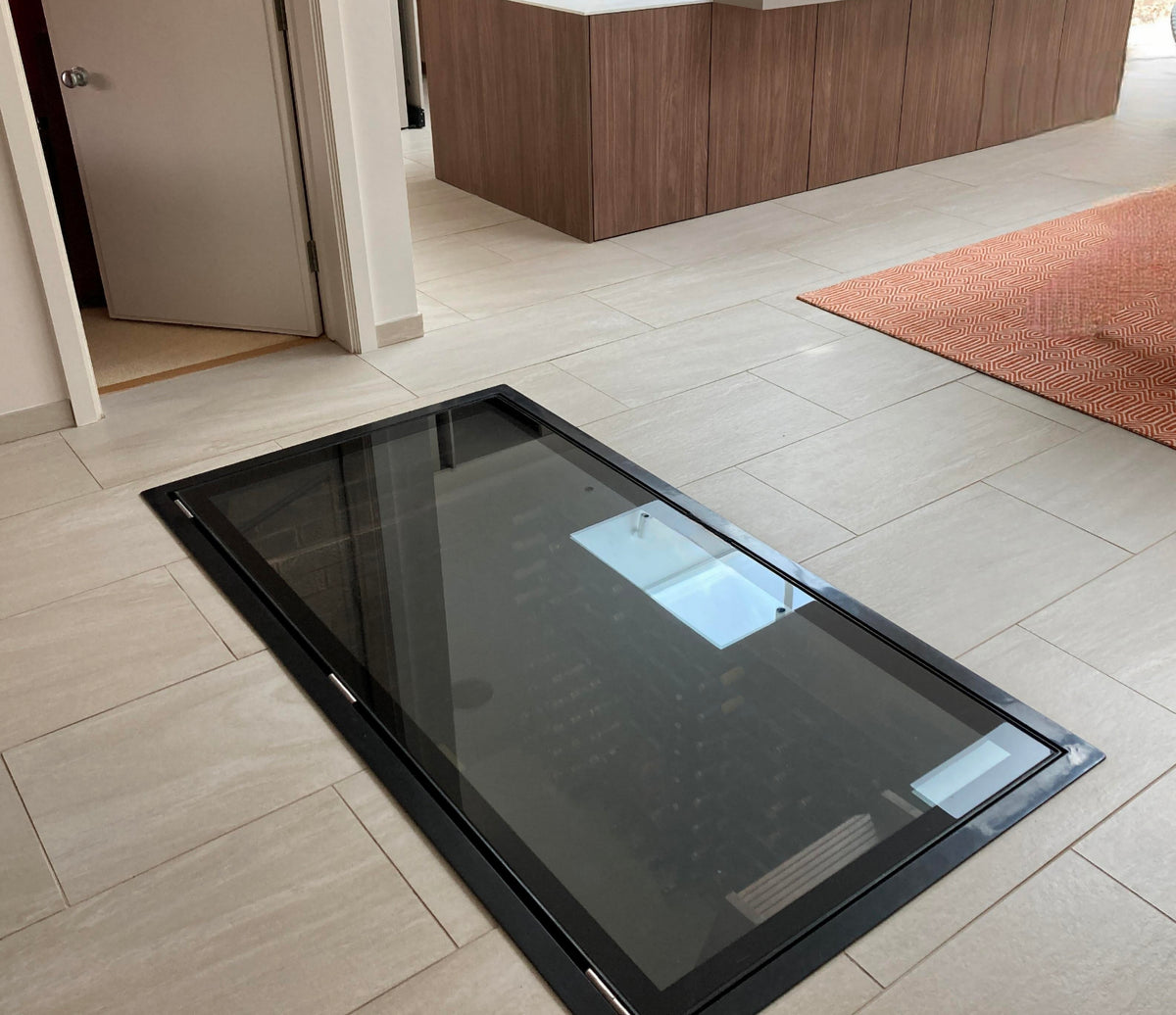 Large electric glass wine cellar door set flush into a tiled kitchen floor, closed