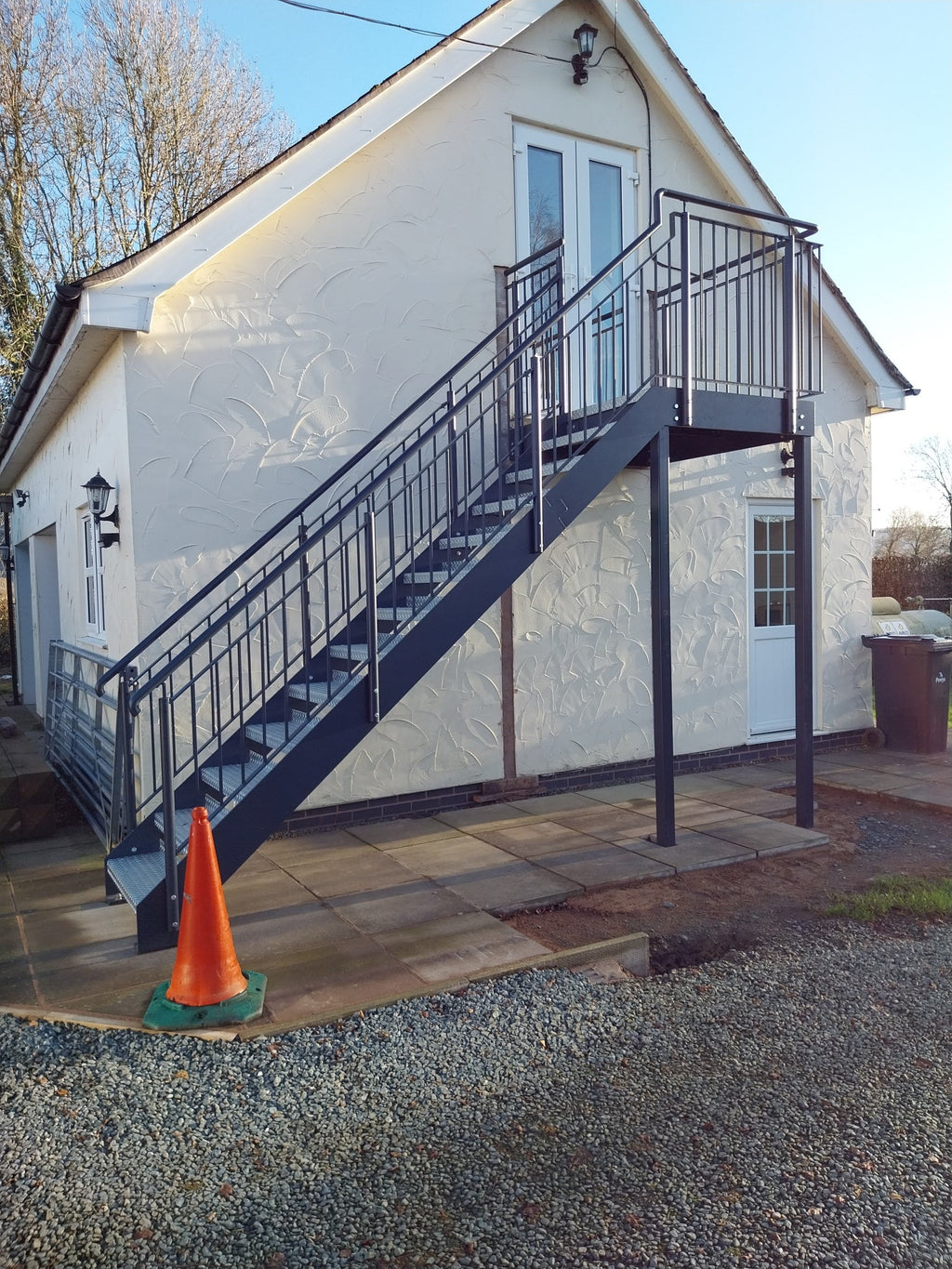 Powder coated external staircase with metal railings and a top landing on support posts