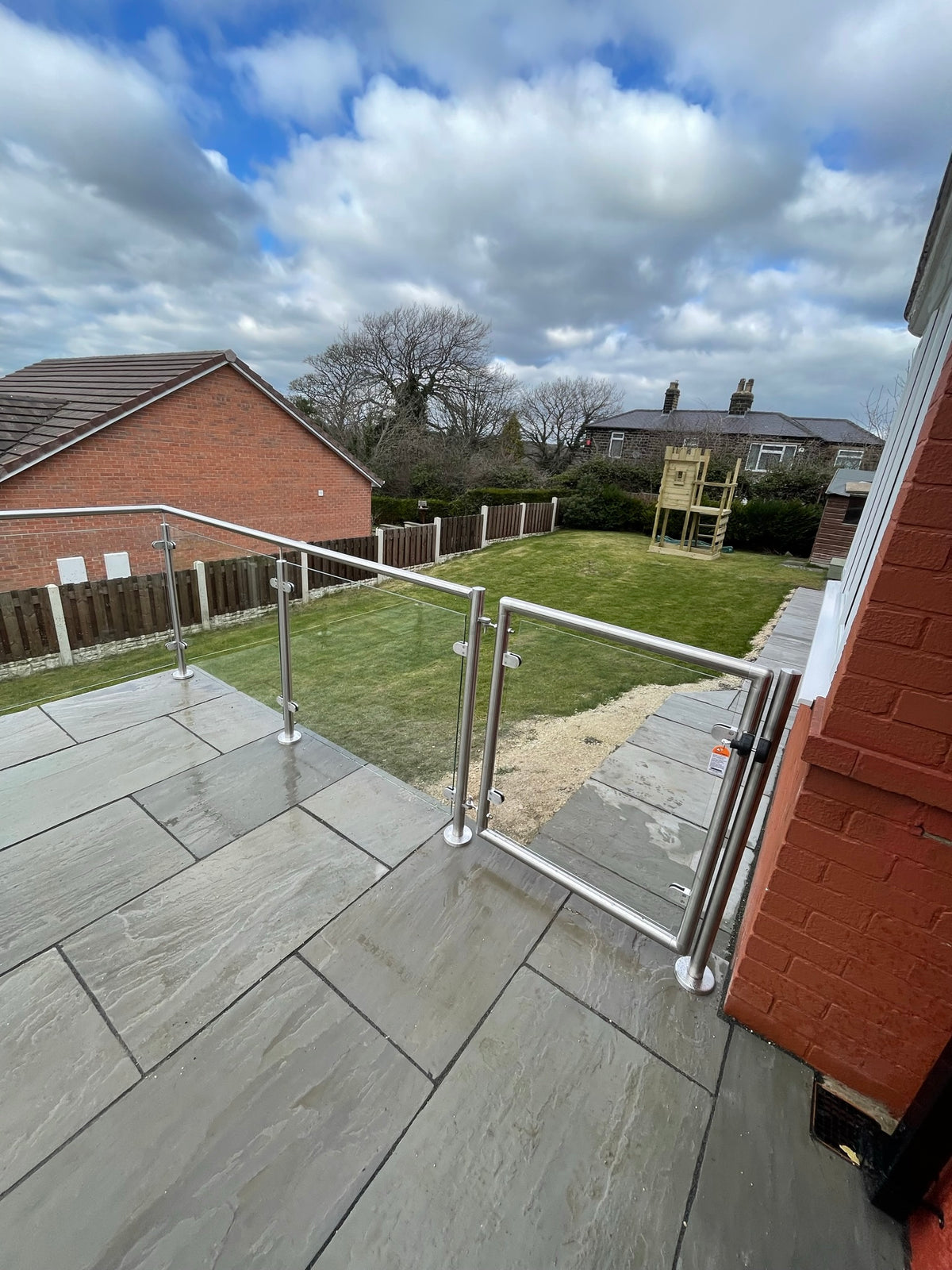 Glass gate at the end of a stainless steel and glass balustrade on a raised patio