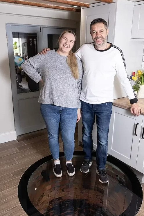 Two people standing on a walk-on glass well cover set into a kitchen floor