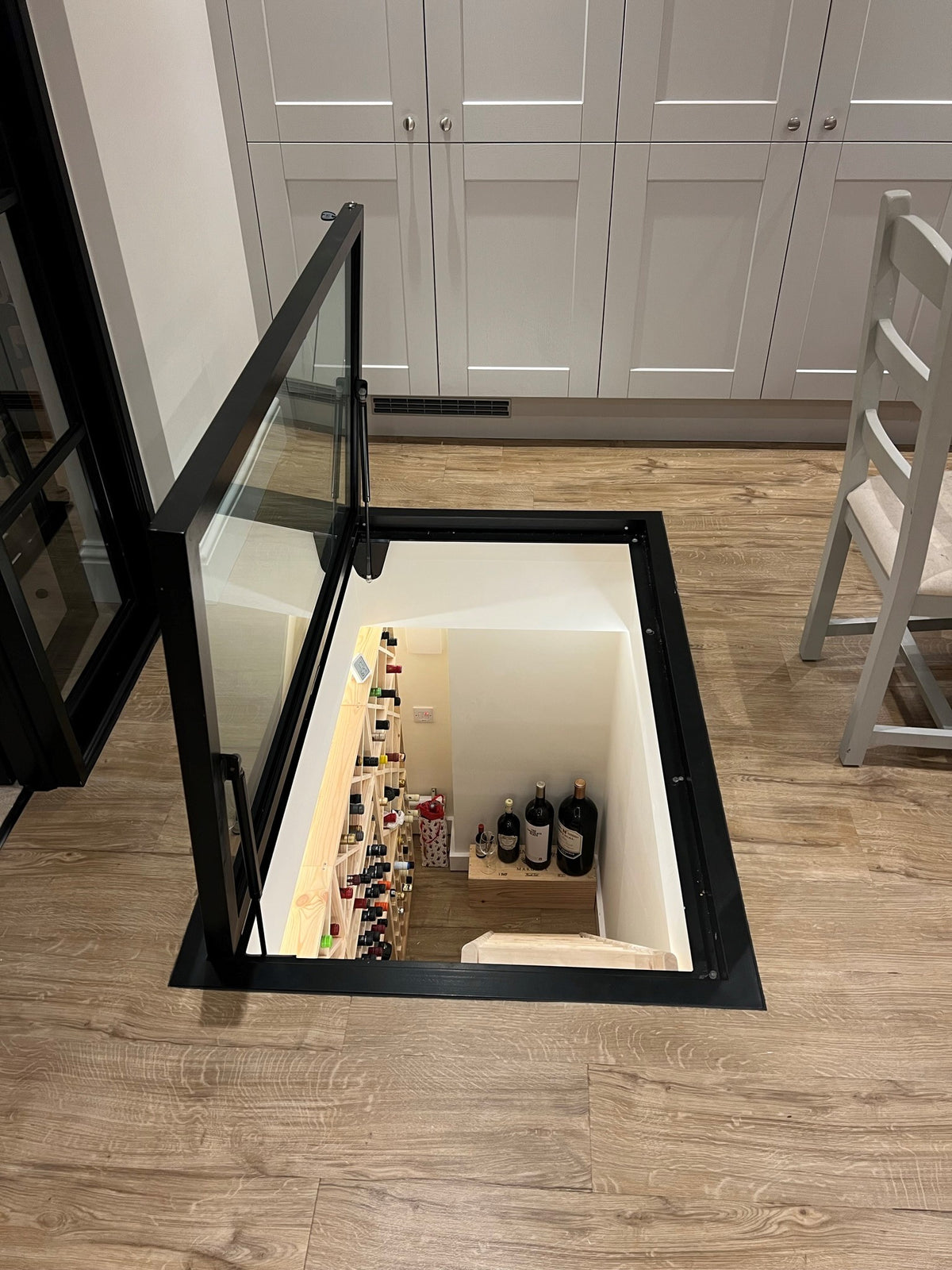 Hinged glass floor door open above wine cellar steps