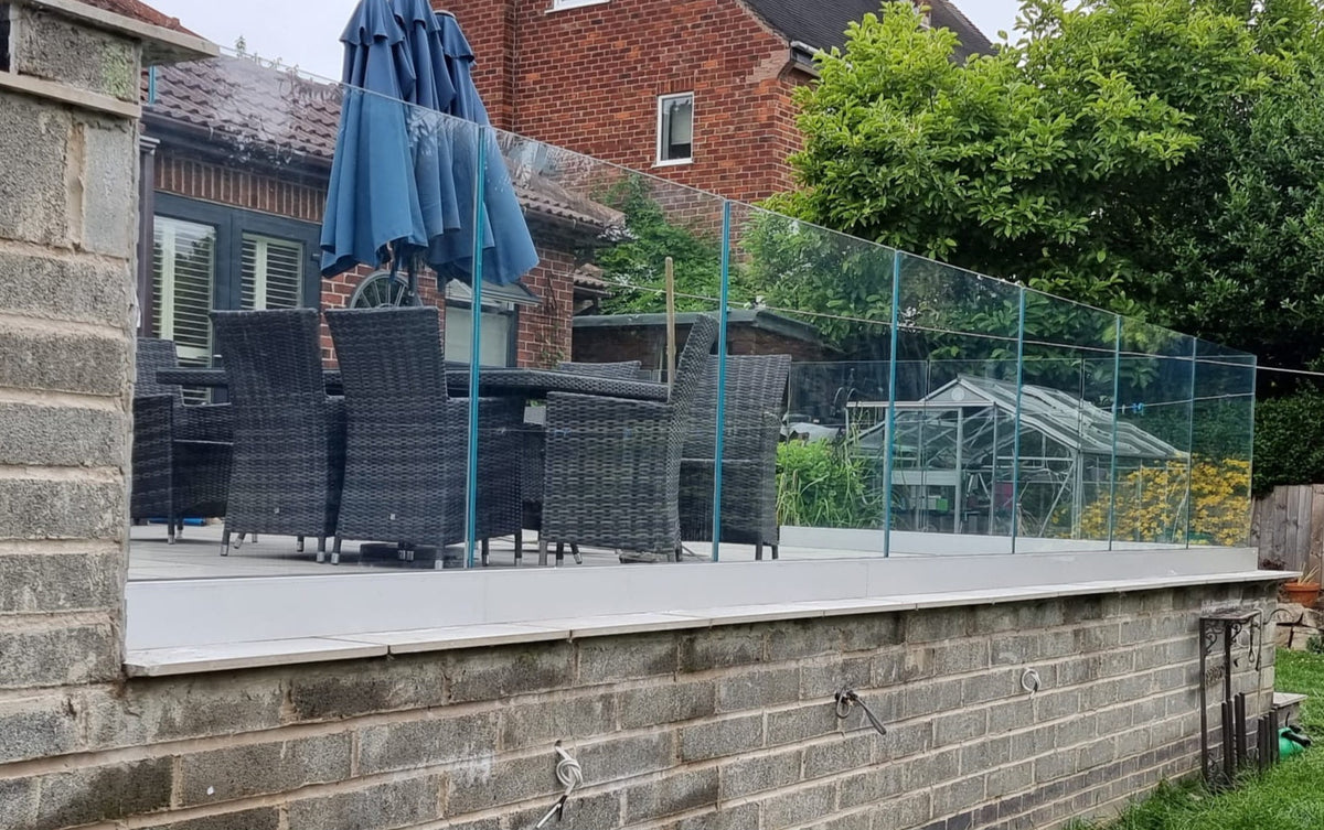Frameless laminated glass balustrade in a base channel along a raised patio edge