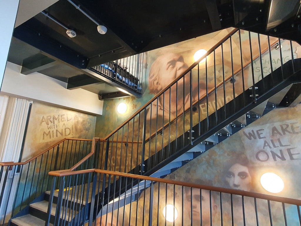 Internal black steel open riser staircase with vertical bar infill balustrade and a timber handrail