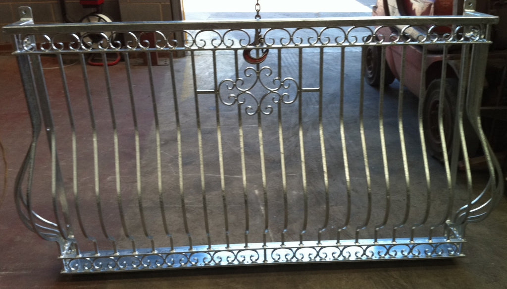 Lancaster curved Juliet balcony in hot dip galvanised finish, showing the scrollwork top and bottom bands and centre motif