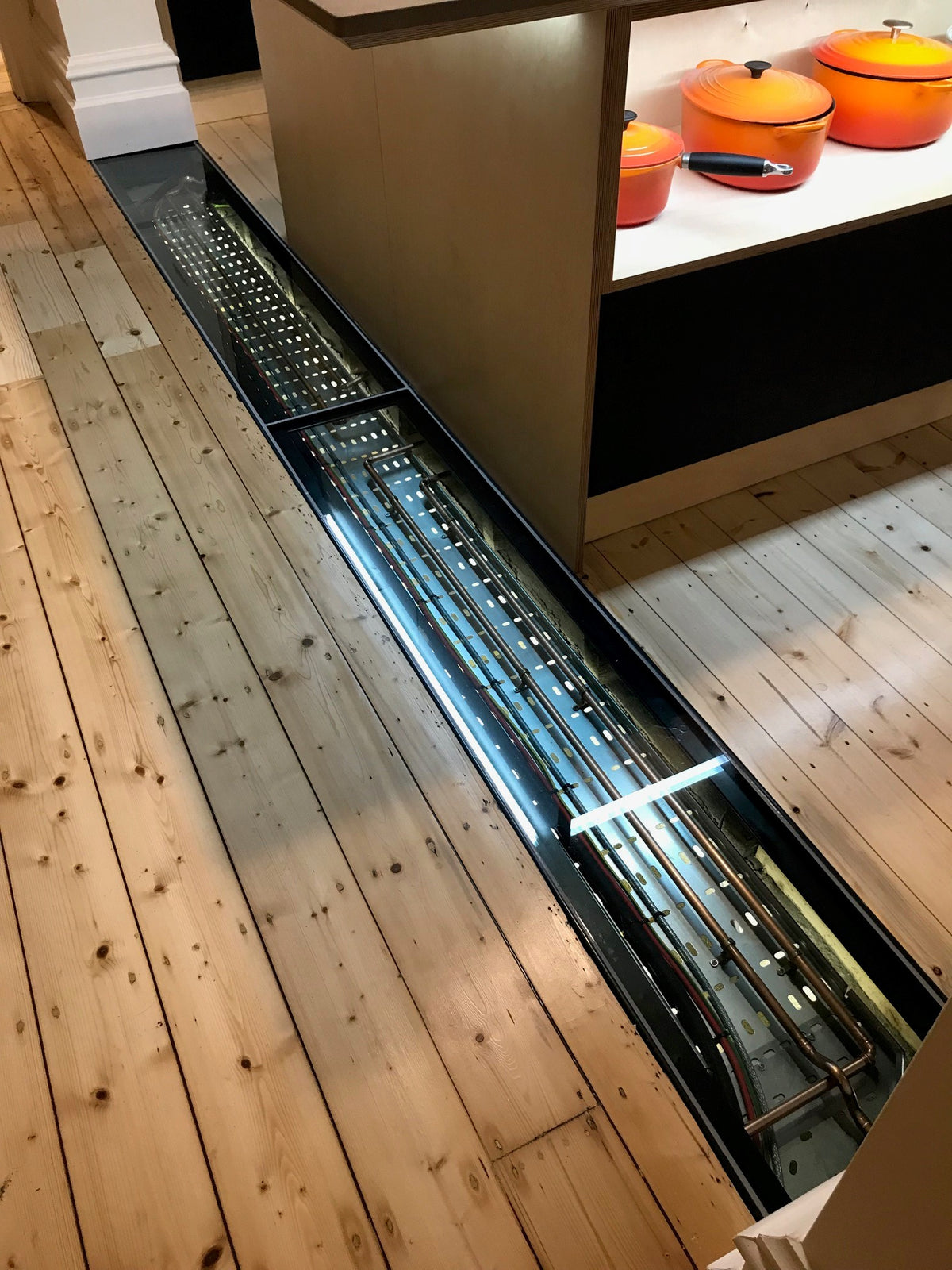 Narrow walk-on laminated glass floor panel set into a kitchen floor above a cellar