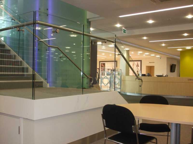Frameless glass balustrade with a handrail mounted on offset brackets along a stair