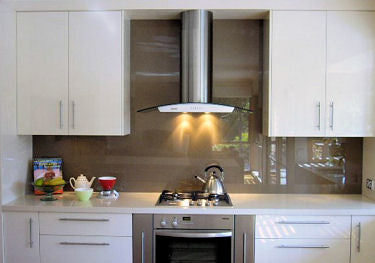 Taupe backpainted glass splashback behind a hob and extractor
