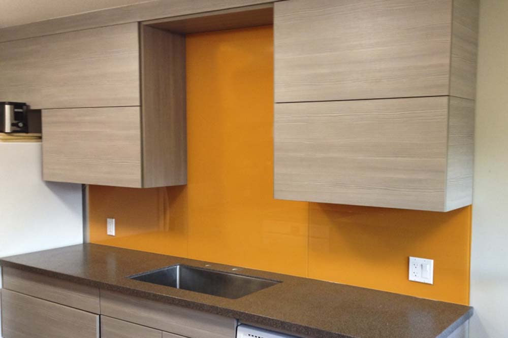 Orange backpainted glass splashback running behind a kitchen sink and worktop