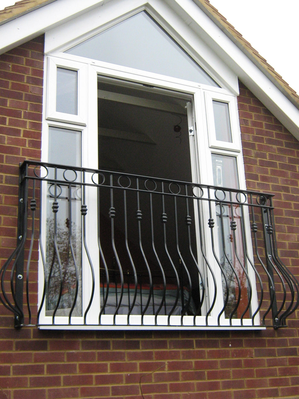 Regency Juliet balcony with ornate circle detail and scrolled side supports on a house gable