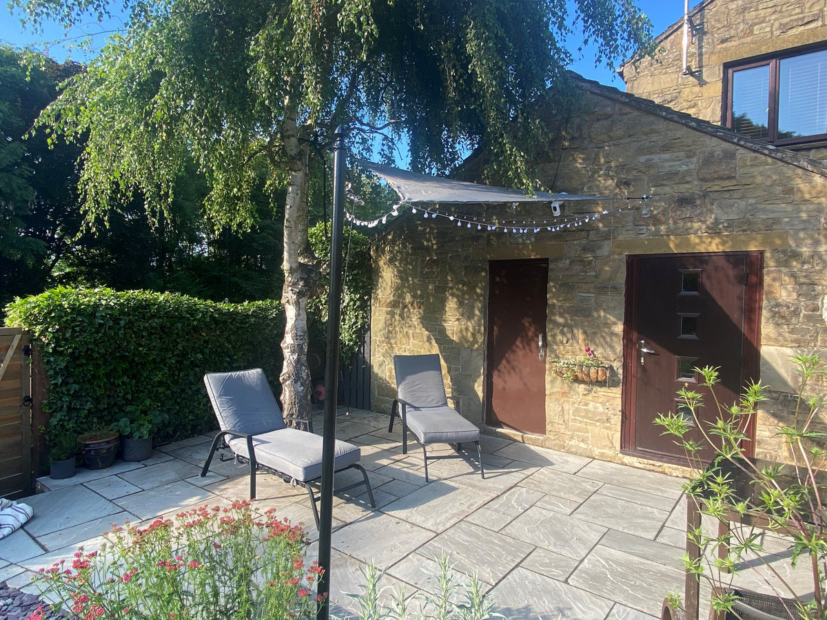 Galvanised steel shade sail posts set in a garden with the sail rigged between them