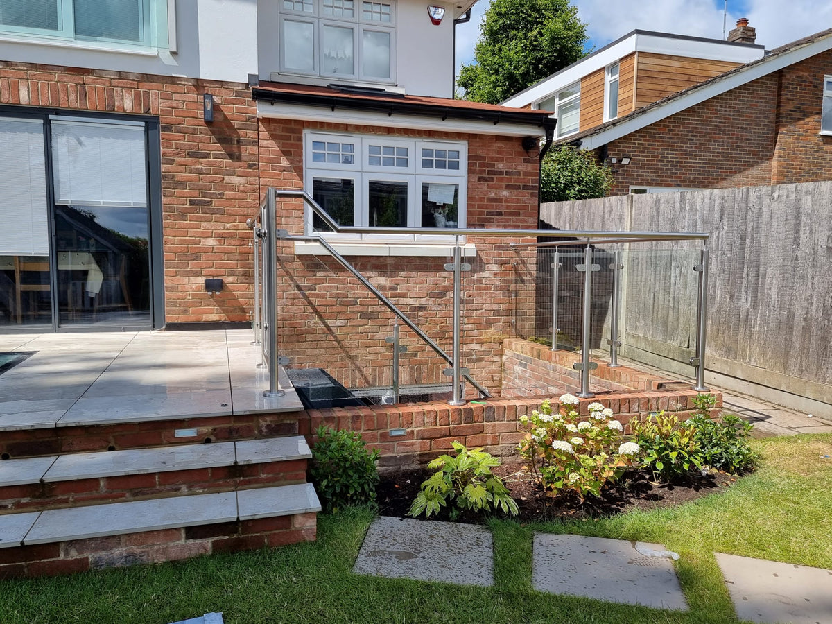 Framed glass gate in a stainless steel and glass balustrade at the head of patio steps