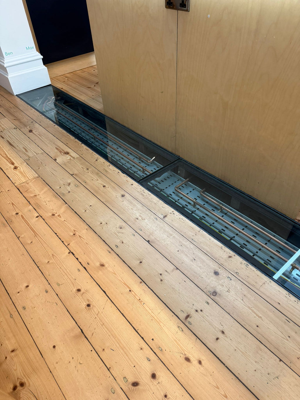Walk-on glass floor panel in a steel frame set into a pine floor