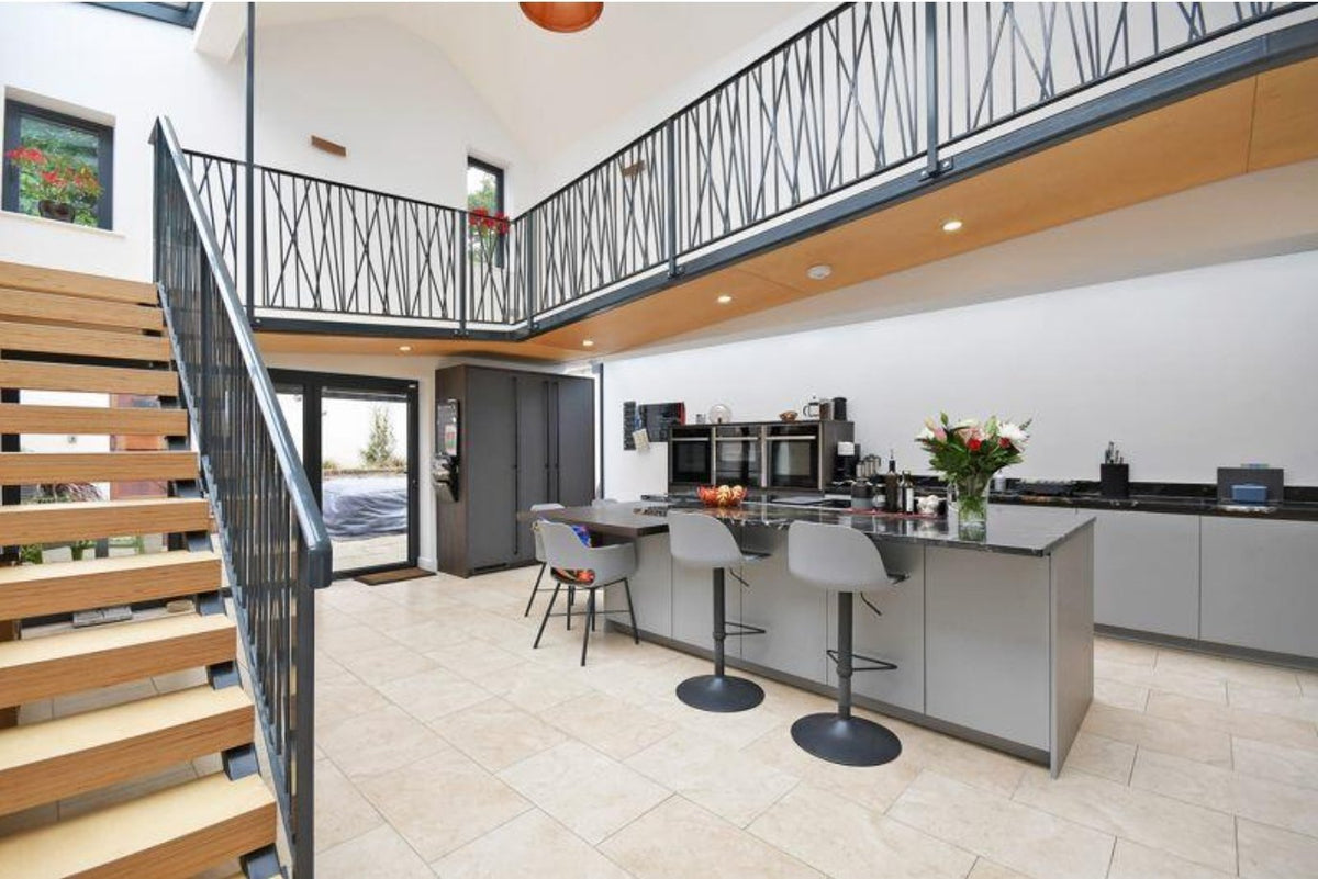 Steel staircase with timber treads and a bespoke metal balustrade running on to a mezzanine
