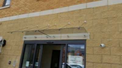 T brackets fixing a glass canopy back to a wall