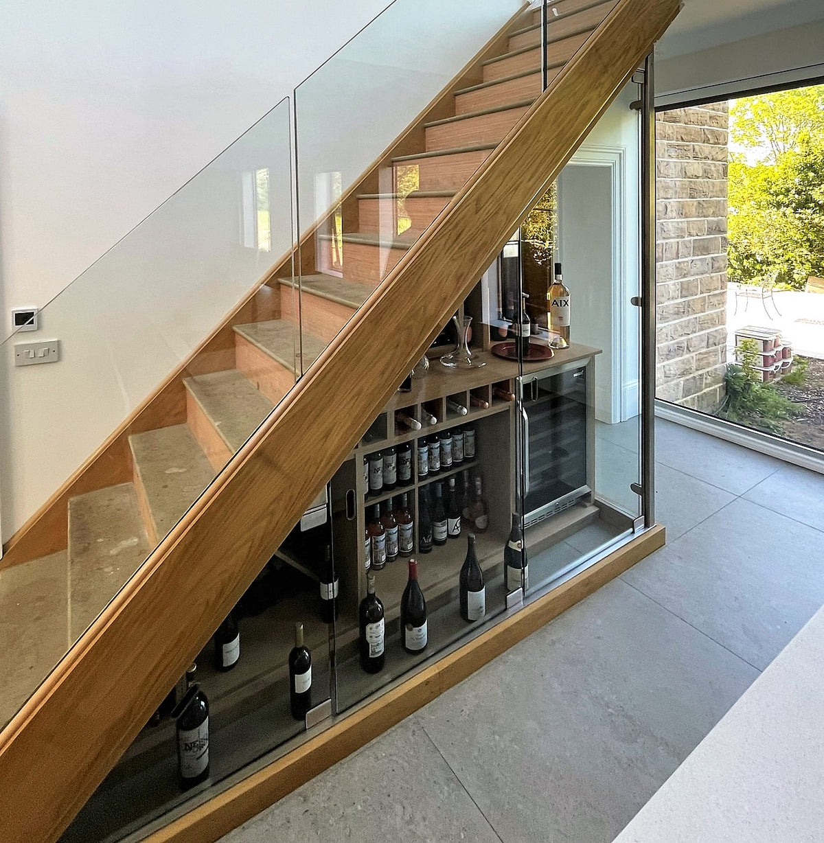 Glass doors fronting a wine cellar built under a staircase