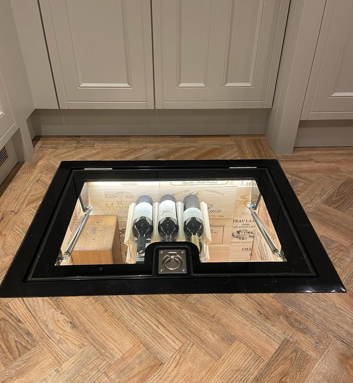 Glass cellar door in a kitchen floor above an underground wine store