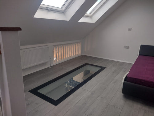 Narrow walk-on glass floor strip in a steel frame set into a loft bedroom floor