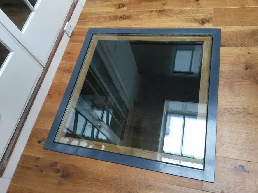 Single walk-on laminated glass floor panel set into an oak floor above a stairwell